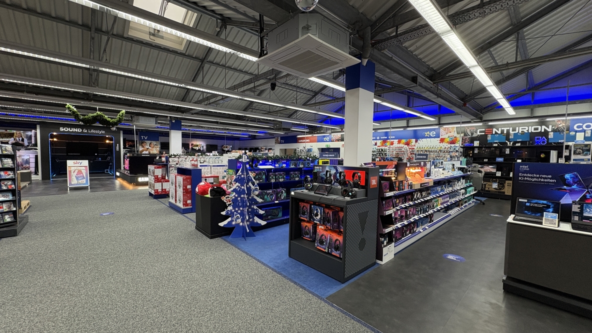Gaming- und Computerabteilung bei EURONICS-Berlet-Bergkamen mit Regalen voller Headsets, Zubehör und Leuchtdisplays, blau beleuchteter Decke und einem dekorativen, blauen Weihnachtsbaum in der Mitte. Gaming- und Computerabteilung bei EURONICS-Berlet-Bergkamen mit Regalen voller Headsets, Zubehör und Leuchtdisplays, blau beleuchteter Decke und einem dekorativen, blauen Weihnachtsbaum in der Mitte.