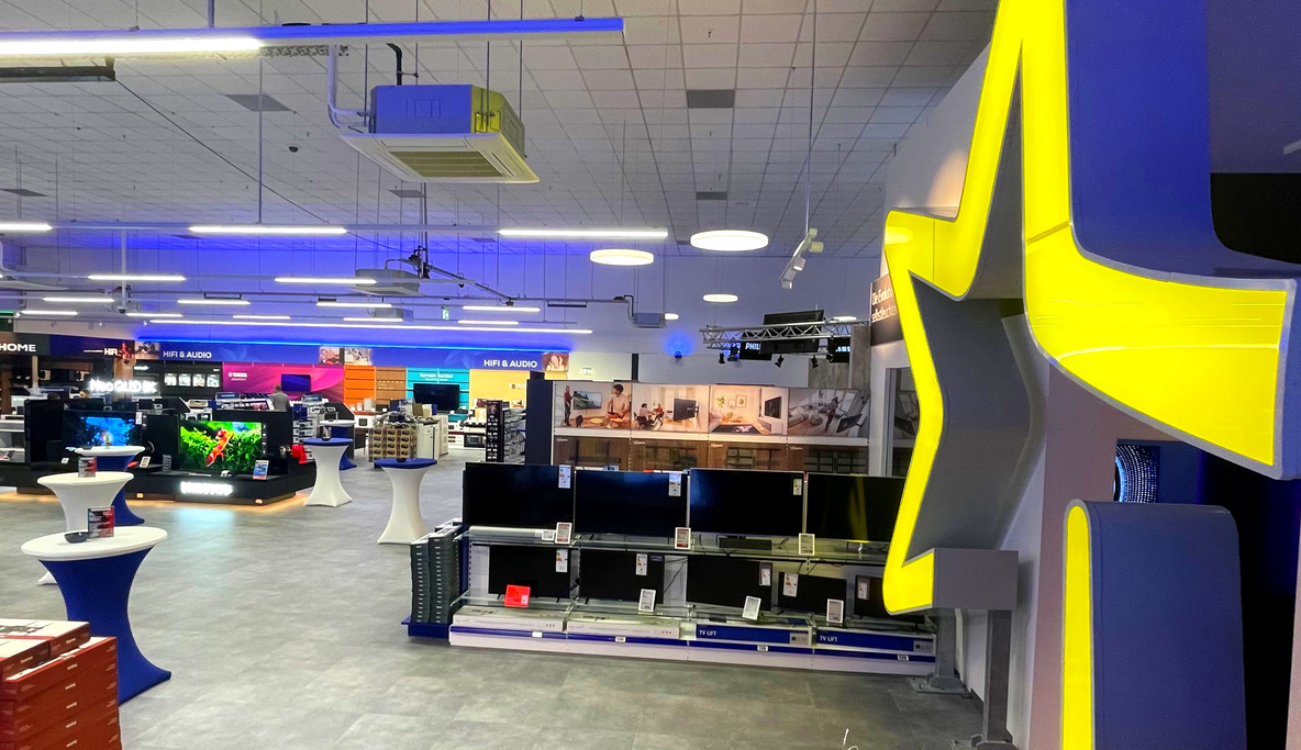 TV-Abteilung bei EURONICS Berlet in Hagen mit Regalen voller Fernseher in der Mitte und leuchtendem EURONICS-Stern rechts, der in den Heimkino-Bereich führt.