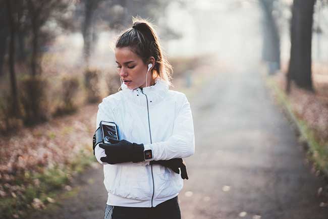 Fitness Tracker verknüpft mit Smartphone: Frau im Park