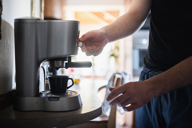 Mann bedient Siebträgermaschine.